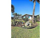 Charming home exterior featuring a lush, landscaped front yard with palm trees and vibrant plants at 134 Gulfview Rd, Punta Gorda, FL 33950