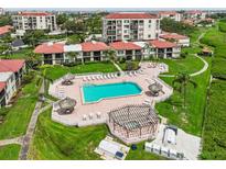 Aerial view of the community pool, complete with tiki huts, lounge chairs, and manicured landscaping at 6218 Palma Del Mar S Blvd # 103, St Petersburg, FL 33715