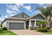 Charming single-story home featuring a brick driveway, a gray garage door, and a covered front porch with columns at 13209 Haystack Ct, Riverview, FL 33579