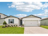 Charming one-story home showcasing a beautiful lawn, brick driveway, and a two-car garage at 1732 Brekey Way, Zephyrhills, FL 33541