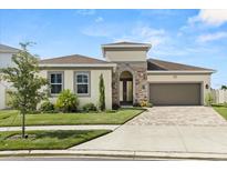 Beautiful single-story home featuring manicured lawn, stone accents and a brick paved driveway leading to a two-car garage at 8297 Ivy Stark Blvd, Wesley Chapel, FL 33545