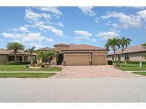 Beautiful home featuring a tile roof, three-car garage, and a well-manicured lawn with palm trees at 20323 Granlago Dr, Venice, FL 34293