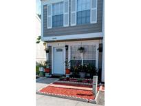 Charming two-story townhome featuring gray siding, white trim, shutters, and a welcoming front entrance with landscaped flowerbeds at 6640 121St Ave # 1, Largo, FL 33773