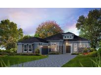 New construction gray home featuring stone accents, professional landscaping, and a paver driveway at 5008 Sea Branch Ave, Apollo Beach, FL 33572