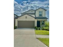 Charming two-story home features a well-manicured lawn, inviting entrance, and attached two-car garage at 9937 Aqua Miles Path, Wesley Chapel, FL 33545