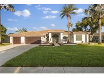 Beautiful one-story home boasts a well-manicured lawn, palm trees and a two car garage at 17032 Winners Cir, Odessa, FL 33556