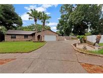 Charming brick home featuring a well-maintained lawn, mature trees, and a two-car garage at 15609 Timberline Dr, Tampa, FL 33624