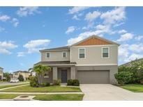 Two-story home featuring a two-car garage, landscaped lawn, and neutral-toned exterior with a welcoming entrance at 12829 Scarlet Star Dr, Riverview, FL 33579