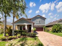 Charming two-story home with a well-maintained yard and a brick-paved driveway under a bright blue sky at 19491 Paddock View Dr, Tampa, FL 33647