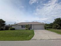 Well-maintained one-story home with a manicured lawn, attached garage, and a concrete driveway at 1140 Belmar Ave, Port Charlotte, FL 33948
