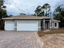 Charming gray home featuring a three-car garage and a brick paver driveway at 1495 Craleigh St, North Port, FL 34288