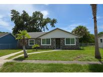 Charming single-story home featuring a stone facade, complemented by a well-manicured lawn and mature trees at 2308 18Th E St, Bradenton, FL 34208