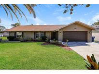 Charming home featuring a well-manicured lawn, complemented by tasteful landscaping, and a two car garage at 3460 Tomahawk Ave, Spring Hill, FL 34606