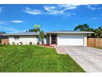 Charming single-story home with a well-maintained lawn and a sunny, blue sky at 1049 Presque Isle Dr, Port Charlotte, FL 33952