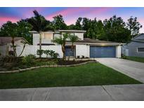 Charming two-story home with blue garage door and landscaped front yard with trees and white brick accents at 4404 Grainary Ave, Tampa, FL 33624