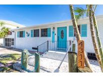 Charming beach house with white brick, aqua door and shutters, and tropical landscaping at 4311 123Rd W St, Cortez, FL 34215
