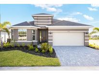 Beautiful single-story home featuring a two-car garage, gray brick driveway, and well-maintained landscaping at 9596 Vibrant Lane, Venice, FL 34292