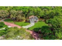 An aerial view of a home surrounded by lush greenery featuring solar panels on the roof at 1300 Pleasant S Way, St Petersburg, FL 33705