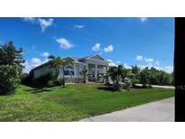 Single story home featuring a landscaped lawn, well-maintained garden and driveway with palm trees at 15301 Chinook Way, Port Charlotte, FL 33981