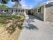 Charming single-story home featuring a stone facade and brick driveway, complemented by verdant landscaping at 5511 Drinkard Dr, New Port Richey, FL 34653
