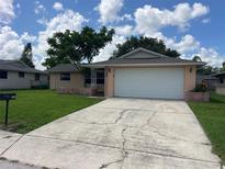 Charming single-story home features a two-car garage and well-maintained front lawn at 7240 Rosarian Dr, Port Richey, FL 34668