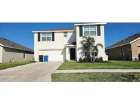 Charming two-story home with a well-manicured lawn and attached two-car garage at 16650 Windmill Forge Pass, Wimauma, FL 33598