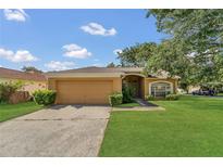 Charming single-story home featuring a lush green lawn and mature trees under a partly cloudy sky at 1236 Sweet Gum Dr, Brandon, FL 33511