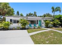 Charming single-story home with lush landscaping, a turquoise door, and a modern design at 707 63Rd S Ave, St Petersburg, FL 33705