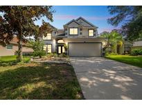 Two-story home with a well-manicured lawn, garden, and a two-car garage at 7716 Nottinghill Sky Dr, Apollo Beach, FL 33572