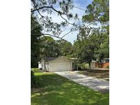 Single-story home featuring an attached two-car garage and long driveway surrounded by mature trees at 9504 W Cluster Ave, Tampa, FL 33615
