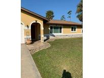 Single-story home with a well-maintained lawn, neutral paint, and welcoming arched entryway at 1409 Yorkshire St, Port Charlotte, FL 33952
