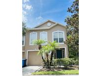 Charming two-story townhome featuring a well-maintained lawn, complemented by two palm trees, and a neutral-toned exterior at 4605 Ashburn Square Dr, Tampa, FL 33610