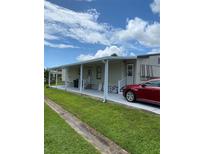 Mobile home with covered patio and carport,red car parked nearby at 6480 Center Lane, North Port, FL 34287