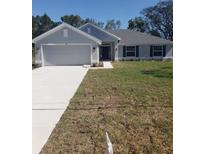 Charming single-story home boasts a two-car garage, gray exterior, manicured lawn, and inviting front entrance at 324 Galaxy Ave, Spring Hill, FL 34606