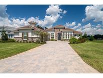 Luxury home with stone accents, tile roof, and paver driveway at 13744 Carryback Dr, Dade City, FL 33525