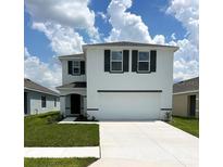Charming two-story home featuring a two-car garage, simple landscaping and a well-manicured lawn at 30908 Wild Juniper Ct, Brooksville, FL 34602