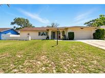 Charming single story home with a well-manicured lawn, front garden, and two car garage at 5078 Kenmore St, Spring Hill, FL 34608