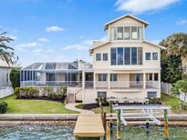 Beautiful waterfront home featuring a dock, large windows, and an inviting outdoor living space with screened-in pool at 849 Harbor Is, Clearwater Beach, FL 33767