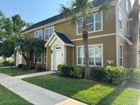 Inviting two-story condo exterior with a lush, manicured lawn and mature palm trees at 5520 Rosehill Rd # 201, Sarasota, FL 34233