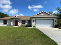 Charming single-Gathering home with a well-manicured lawn and a two-car garage on a sunny day at 1608 Alliance Ave, North Port, FL 34286