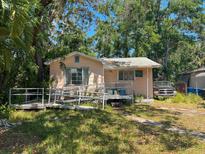 Exterior view of a single-story home with a ramp and overgrown landscaping at 665 36Th S Ave, St Petersburg, FL 33705