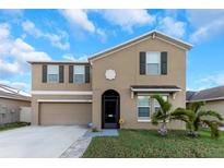 Two story home featuring a tan exterior, well maintained lawn and attached two car garage at 1739 Broad Winged Hawk Dr, Ruskin, FL 33570