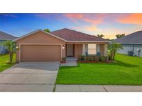 Charming single-story home featuring a well-manicured lawn, a two-car garage, and beautifully landscaped front yard at 6812 Gideon Cir, Zephyrhills, FL 33541