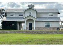 Charming two-story home with a metal roof and well-maintained landscaping, exuding curb appeal at 15200 Rawls Rd, Sarasota, FL 34240
