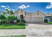 Two-story house with beige exterior, three car garage, and landscaped yard at 5330 Silver Sun Dr, Apollo Beach, FL 33572