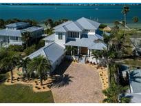 Stunning waterfront home featuring lush landscaping, a gray metal roof, and a brick paver driveway at 764 S Mccall Rd, Englewood, FL 34223