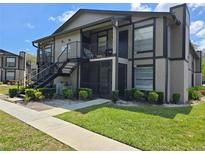 Two-story condo with an exterior staircase, screened in patio, and landscaping at 14663 Norwood Oaks Dr # 103, Tampa, FL 33613