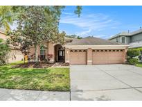 Charming one-story home with a well-manicured lawn and a two-car garage on a sunny day at 11924 Northumberland Dr, Tampa, FL 33626