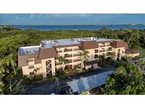 Coastal condo building with balconies, mature landscaping, and covered parking near the water at 23465 Harborview Rd # 223, Punta Gorda, FL 33980