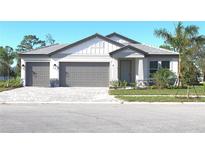 Beautiful two-car garage home featuring gray and white design, complemented by lush green landscaping and paver driveway at 1504 Lugano Cir, Nokomis, FL 34275